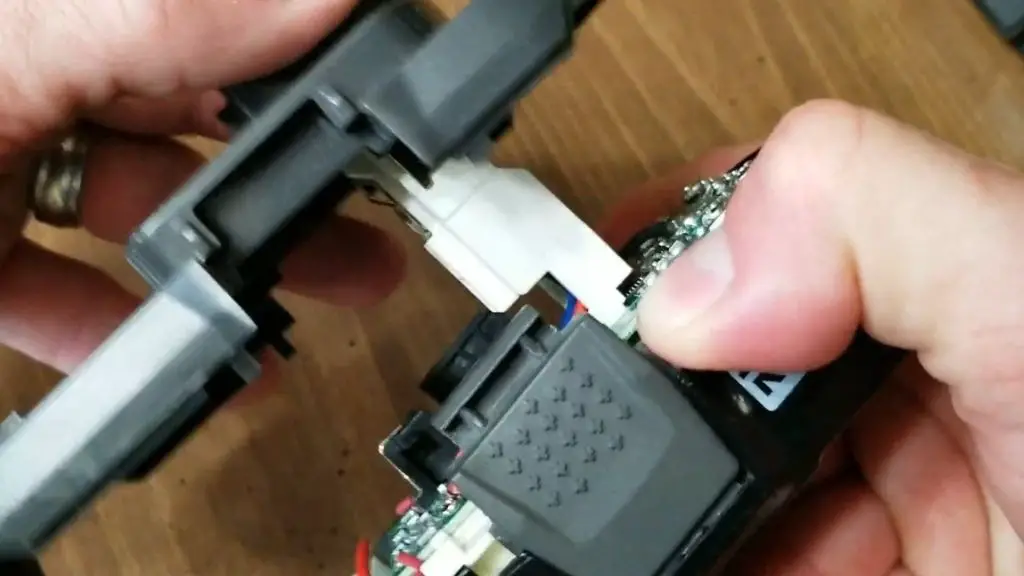 Image showing how to use your thumb and index finger to support the battery control module as you separate the battery case on a Ryobi 18v battery.
