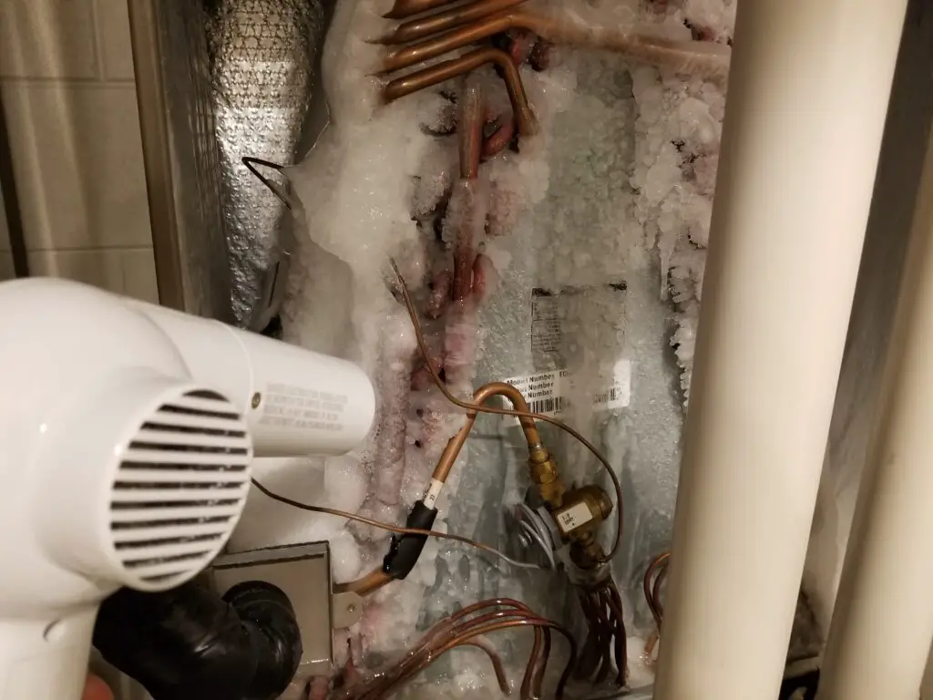 image showing author using a blow dryer to thaw a frozen HVAC system.  